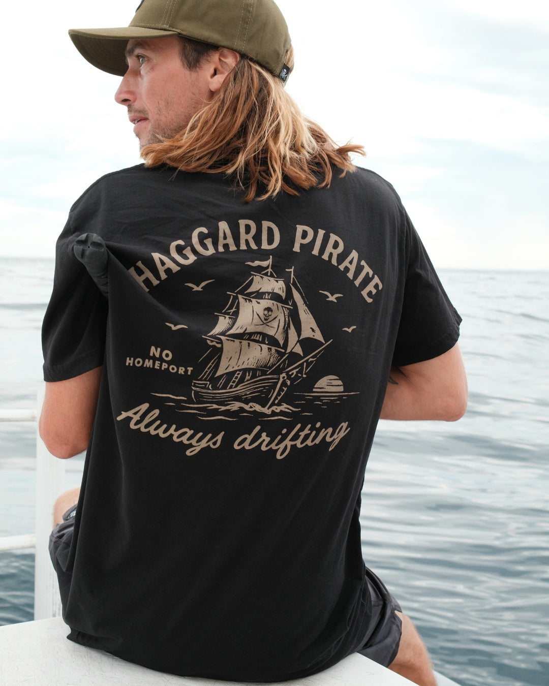 Black Endless Drift Tee worn on the boat, showing the sailing ship back graphic